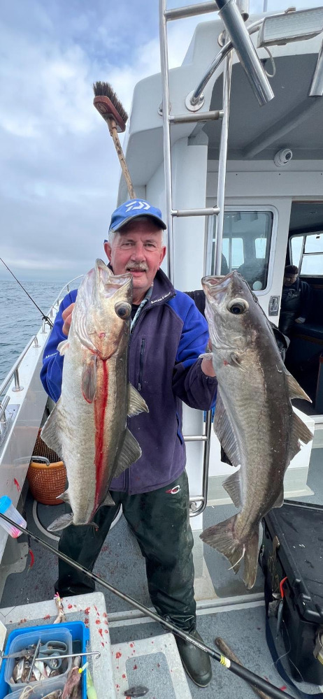 man holds up two large fish